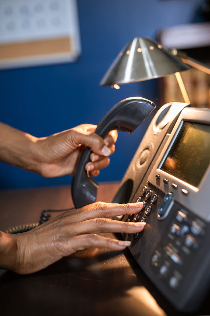 Crafting Captivating Headlines: Your awesome post title goes here A person dialing a phone call on a desk telephone, focusing on hand details.